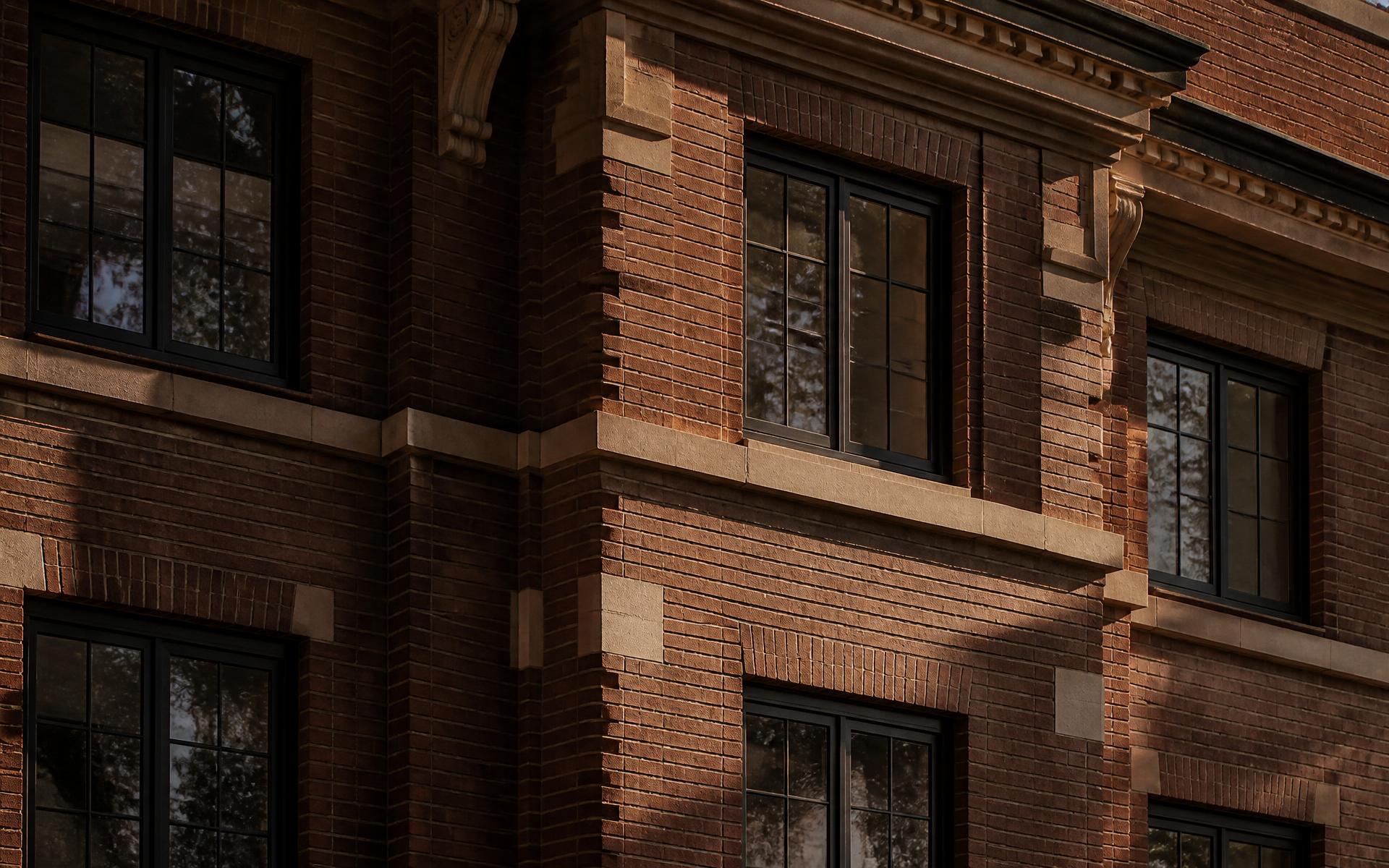 Detail of a 1930s Denver brick multifamily building: masonry, limestone banding and steel windows